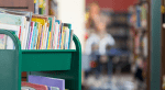 A return book cart is filled with children's books inside a library.