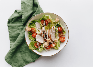 Bowl with salad and dressing sits on a green tea towel.