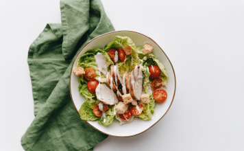 Bowl with salad and dressing sits on a green tea towel.