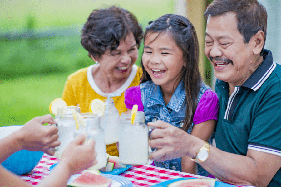 Happy grandparents and granddaughter have a picnic outside for Grandparent's Day.