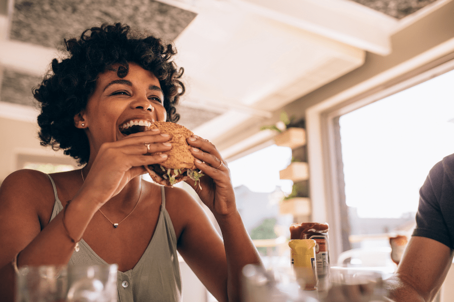 Happy woman bites into a free sub sandwich at a restaurant.