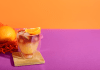 Orange cocktail drink on a pink and orange background.