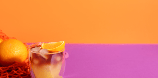 Orange cocktail drink on a pink and orange background.