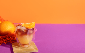 Orange cocktail drink on a pink and orange background.