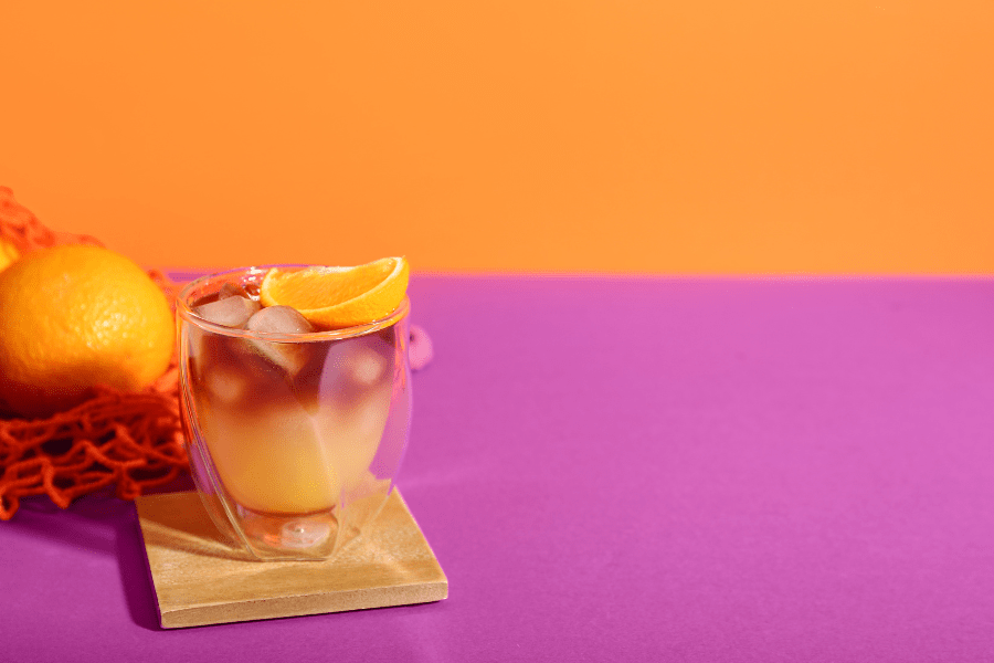 Orange cocktail drink on a pink and orange background.