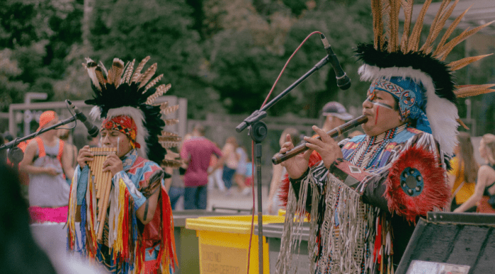 Native Americans play instruments in traditional attire.