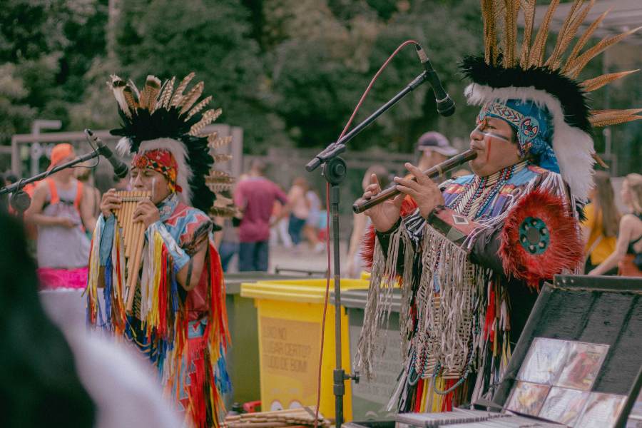 Native Americans play instruments in traditional attire.