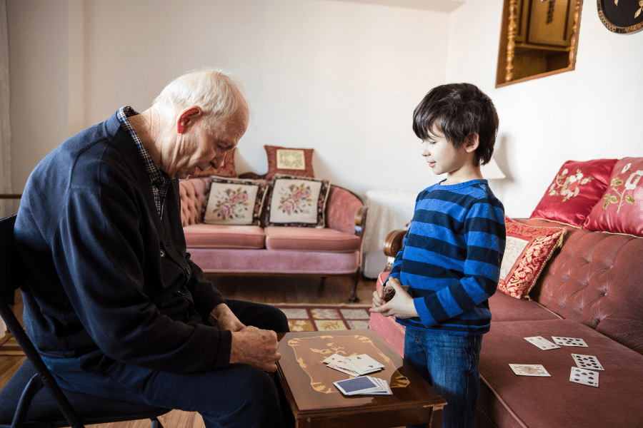 Grandpa and grandson play a card game in the living room.