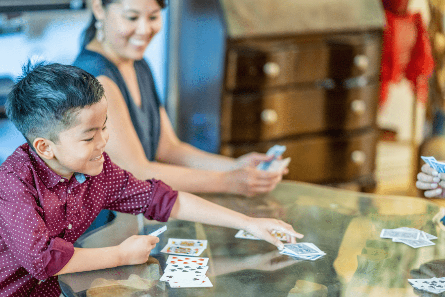 Mother and son play a card game together at the table.