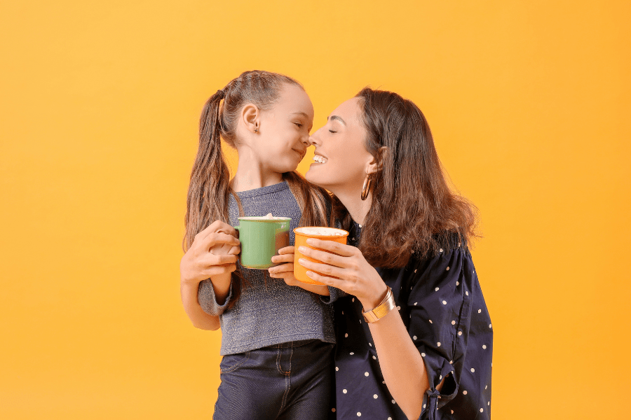 Mom and daughter drink cocoa and snuggle together.