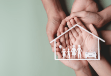 Hands hold the shape of a home and family and car.