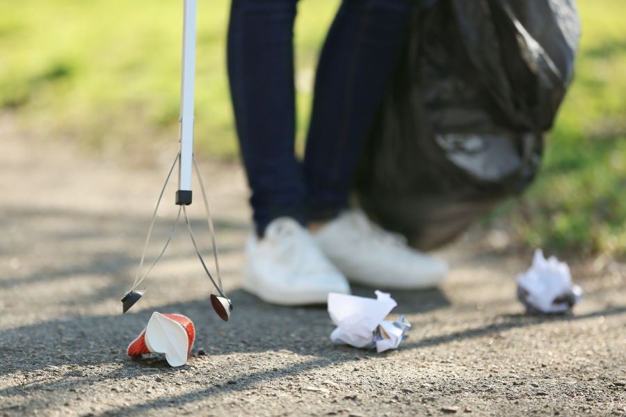 Person picks up litter outside and puts it in a trash bag